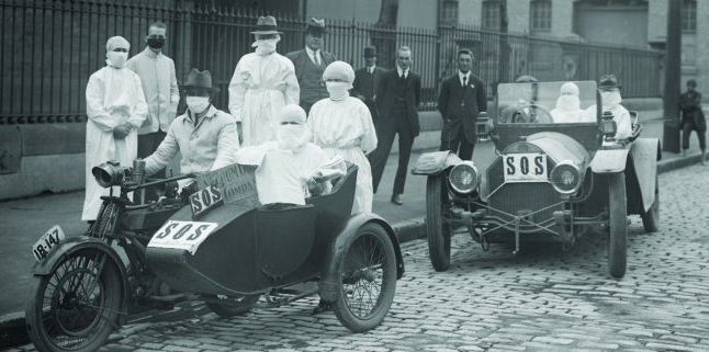 Medical staff in protective gowns and masks with two SOS-marked vehicles, including a motorcycle sidecar and an open car, during the 1918–1919 Spanish flu outbreak in Sydney.